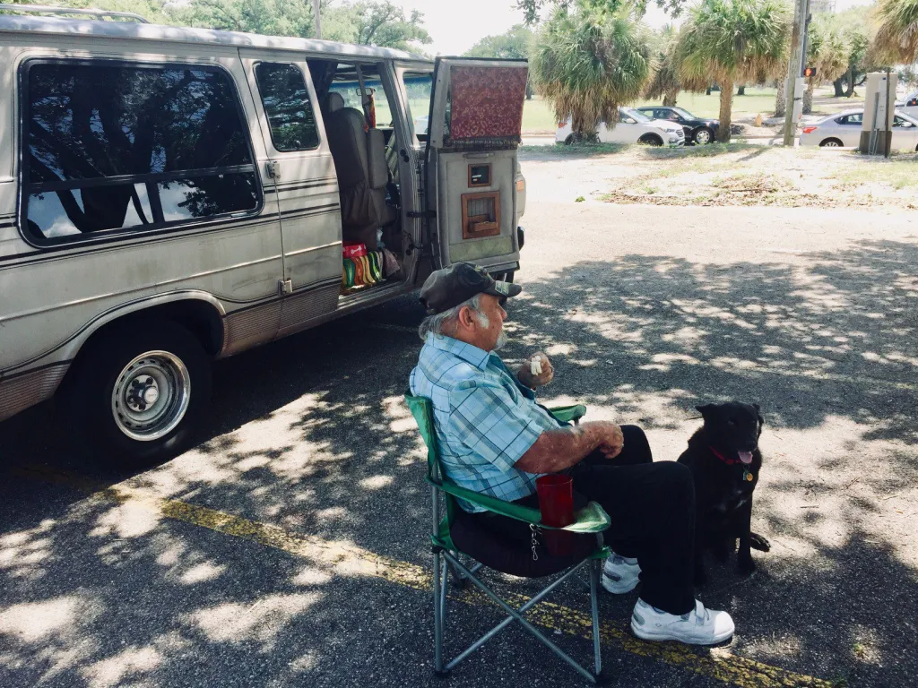 Man sitting in chair in front of motor vehicle