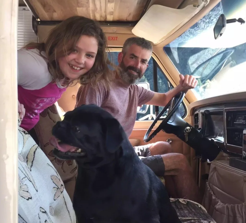 Dad, daughter and dog driving RV.