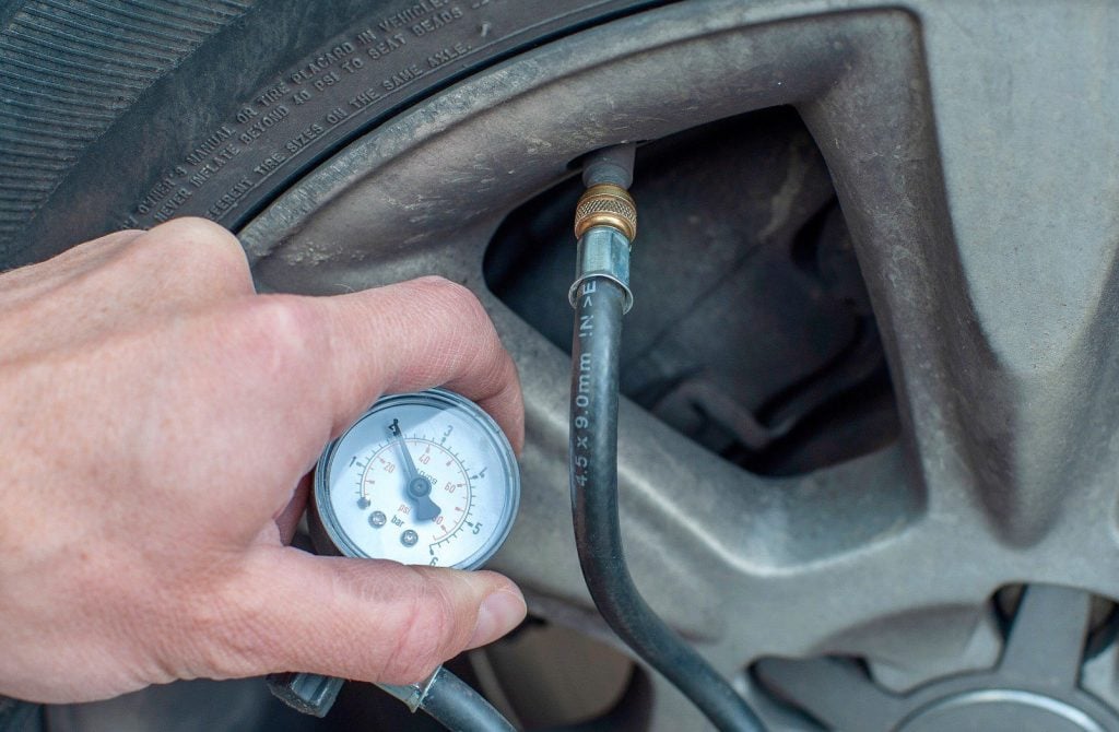Checking tire pressure on a vehicle.