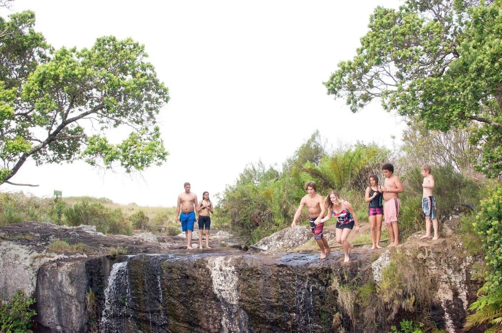 Friends jumping into swimming hole.