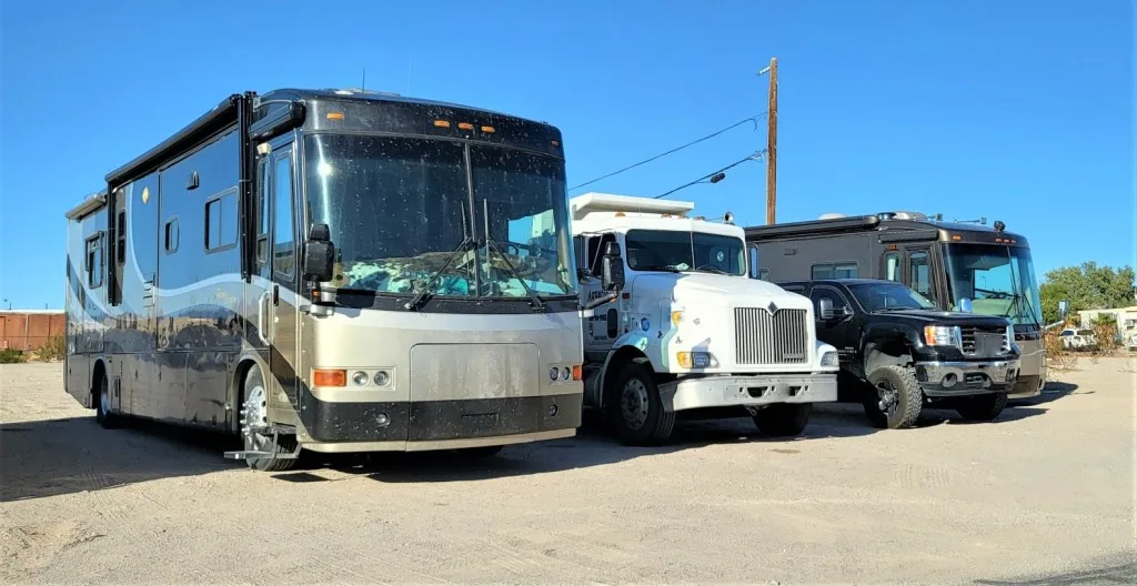 Toterhome parked between two buses.