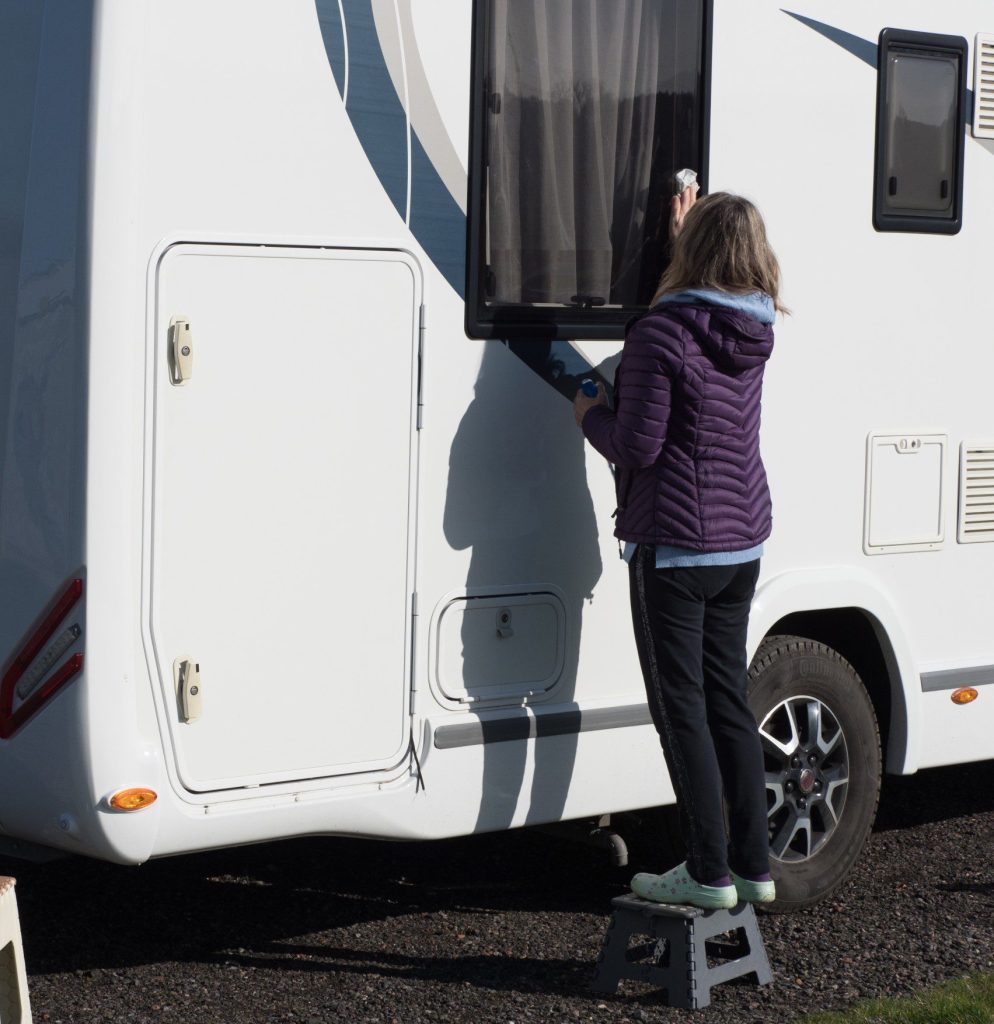 Woman cleaning and checking RV exterior