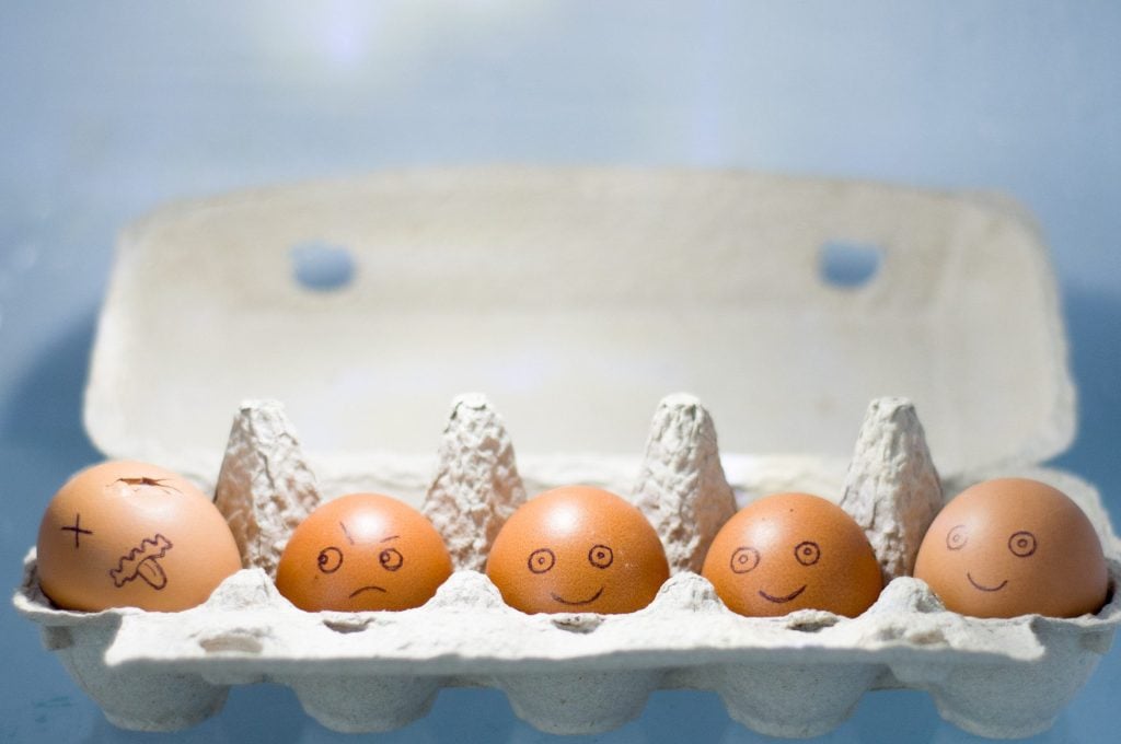 Eggs with faces lined up with one rotten egg.