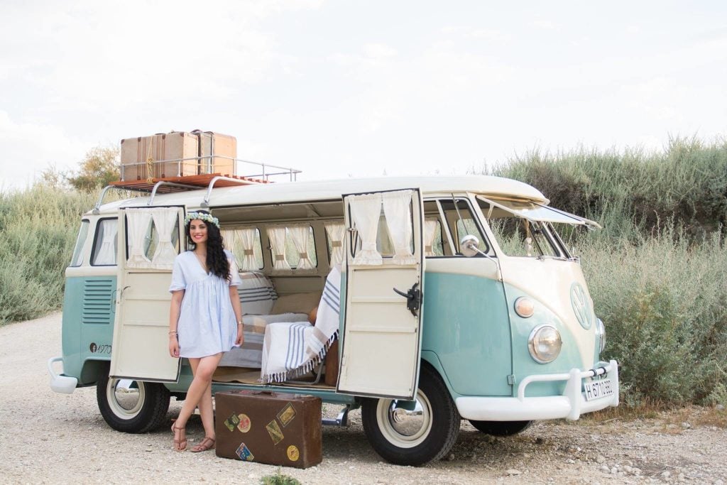 Woman posing in front of vintage camper van.
