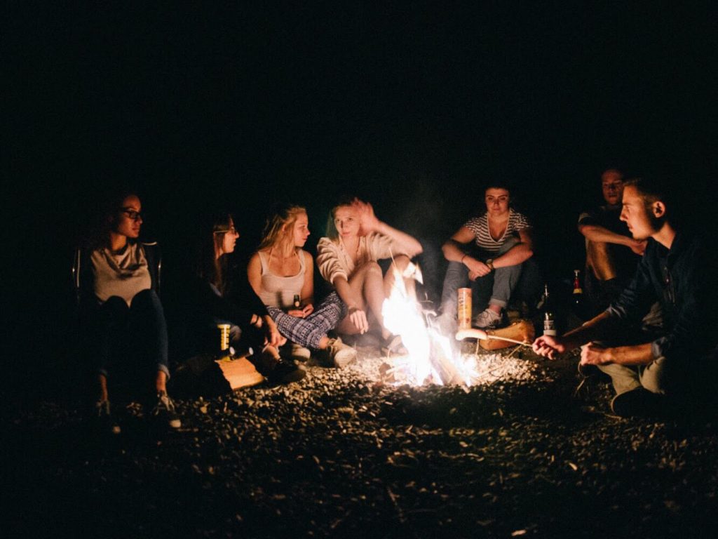 Friends sitting around bonfire on a camping trip.
