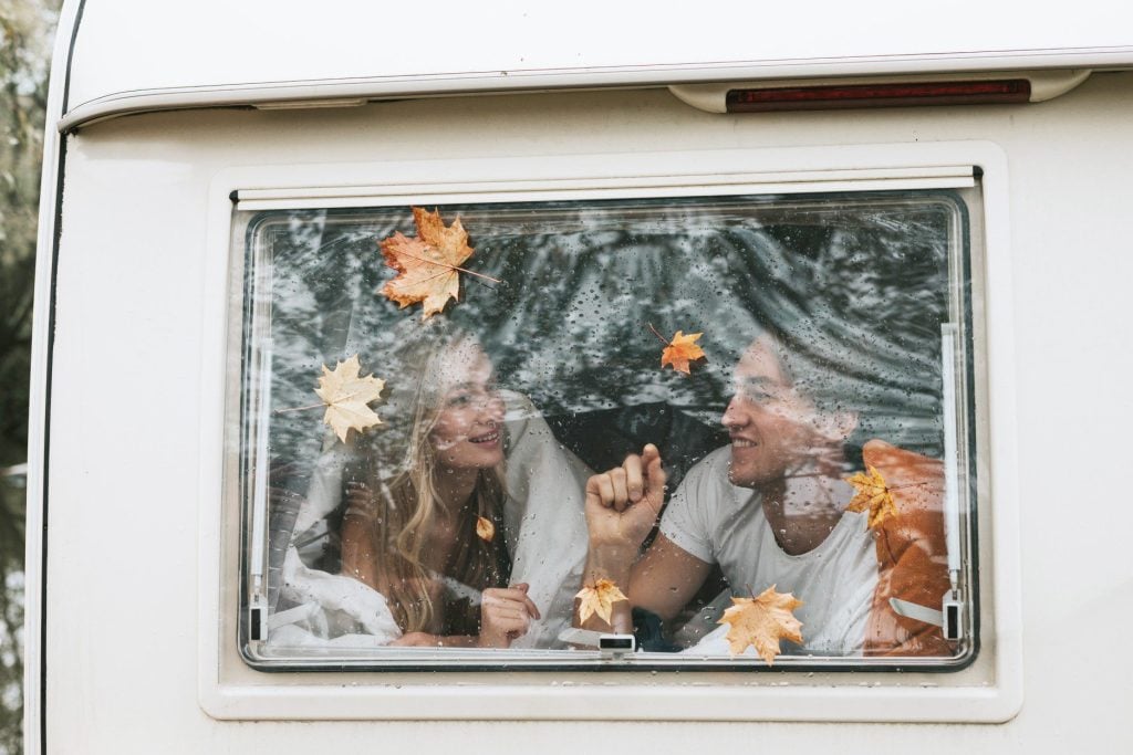 Couple laying in bed in front of RV window.