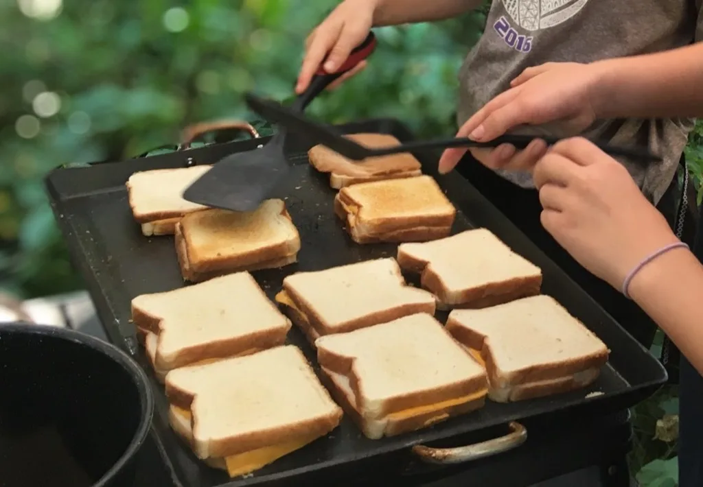 Kids making grilled cheese on a griddle.