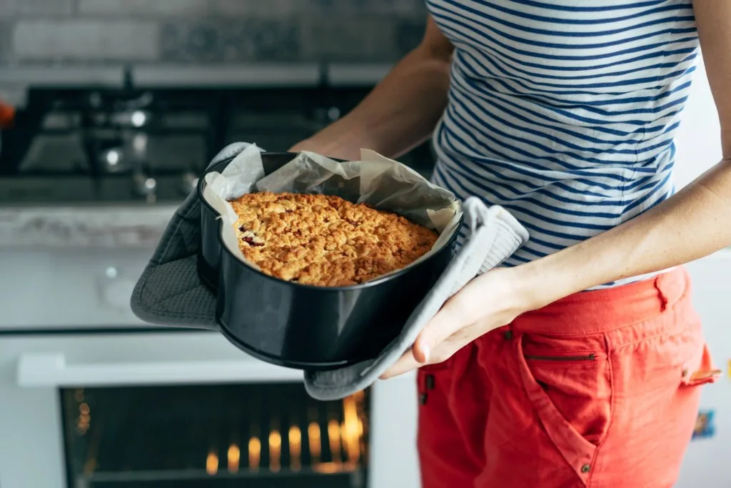 Woman baking cake in oven
