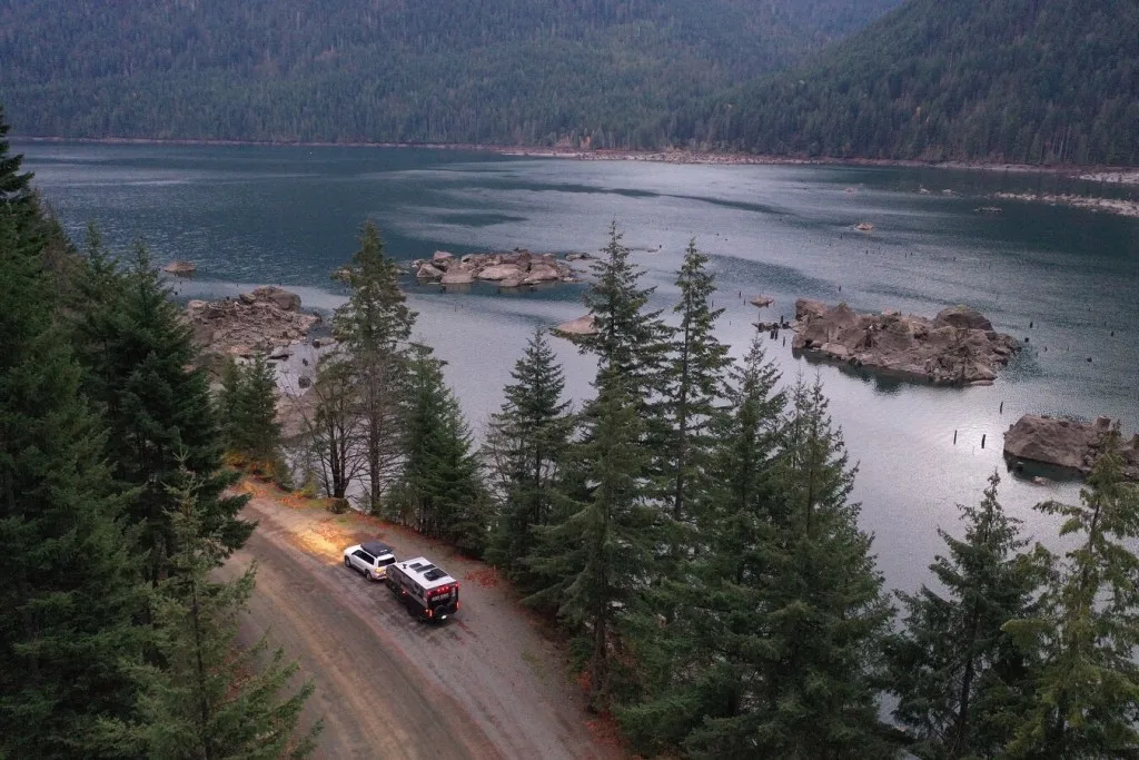 Aerial image of SUV towing travel trailer next to lake.