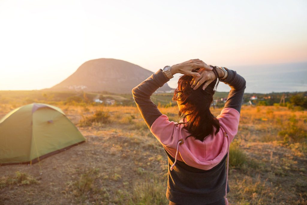 Woman posing in front of tent while camping.