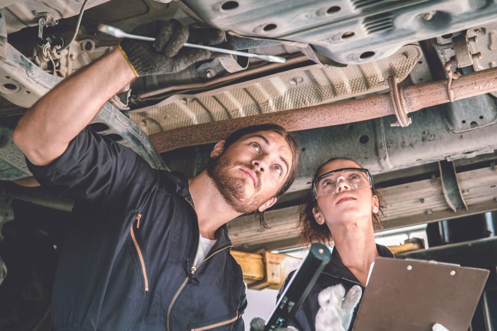 Male and female mechanic repairing car.