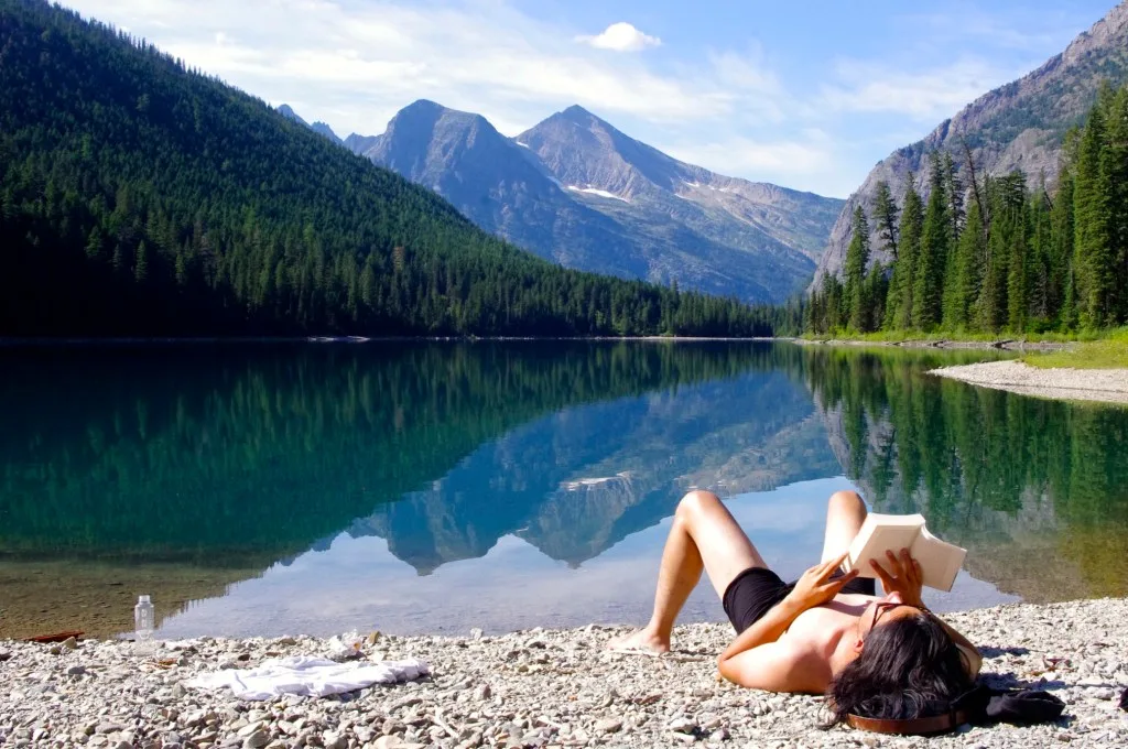 Woman reading by lake in Glacier National Park