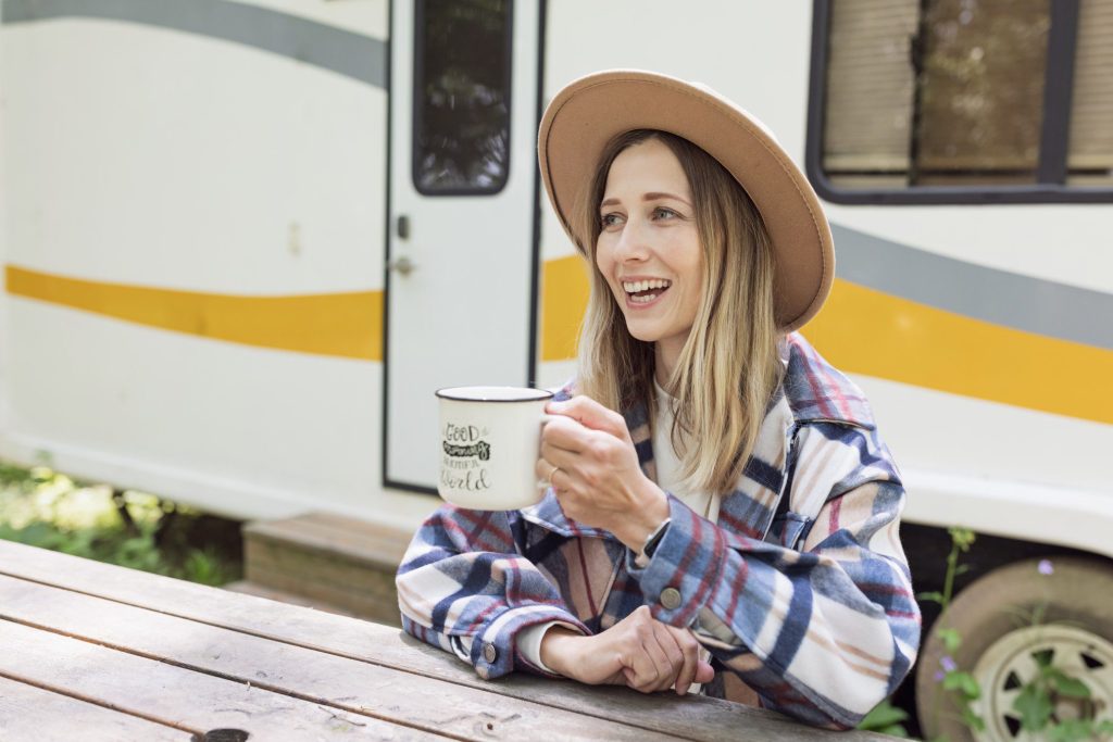 Woman happily drinking coffee in front of RV.