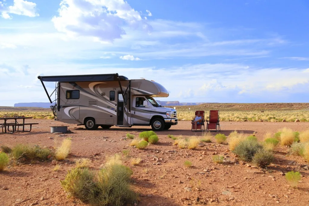 Woman sitting in front of RV while boondocking in BLM land.