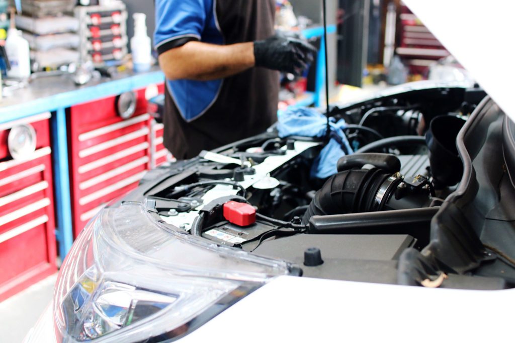 Mechanic repairing engine on vehicle 