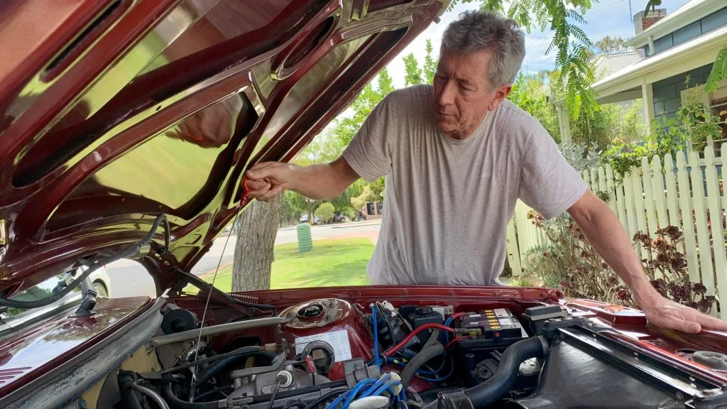 Man looking at vehicle engine to do repairs