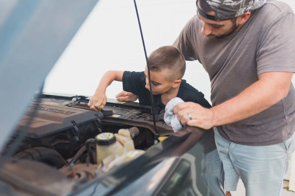 Father and son changing oil on vehicle.