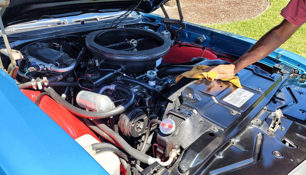 Man cleaning engine bay with rag