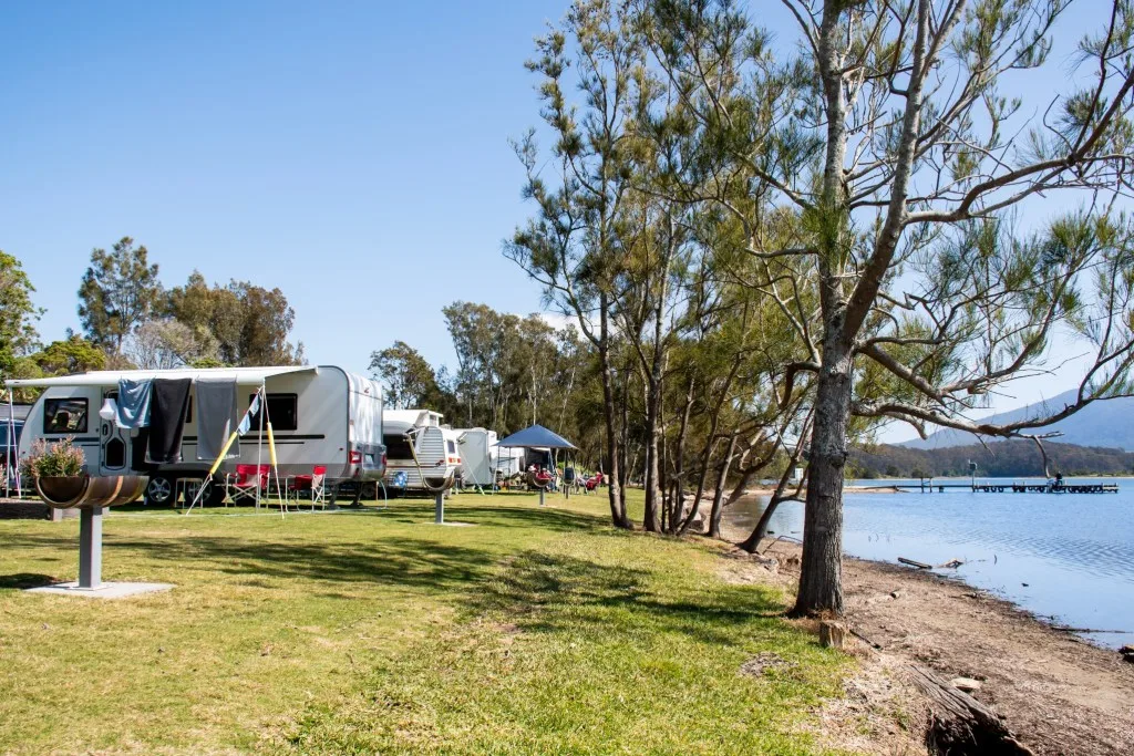 RVs parked along a lake at campsite.