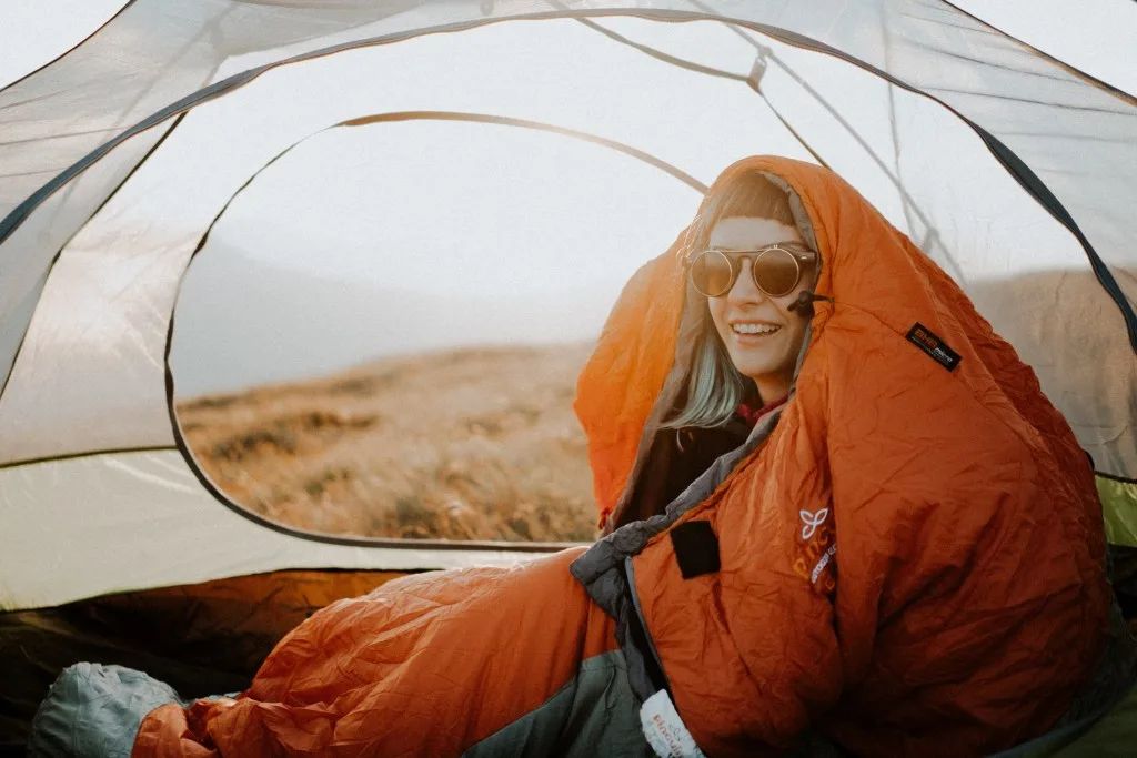 Woman sitting in sleeping bag in tent