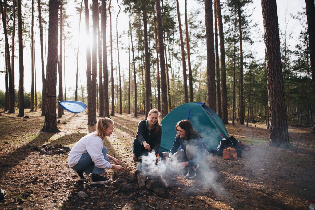 Three women friends camping in woods.