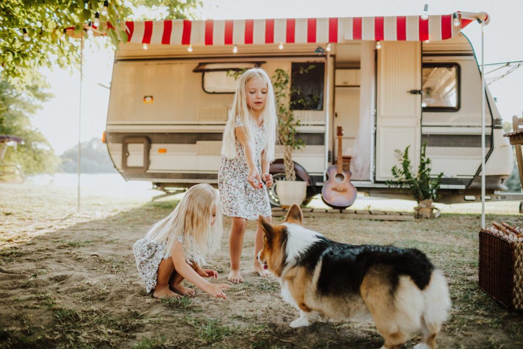 Two little girls and corgi playing in front of RV