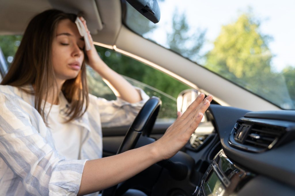 Woman sweating in vehicle with broken air conditioning