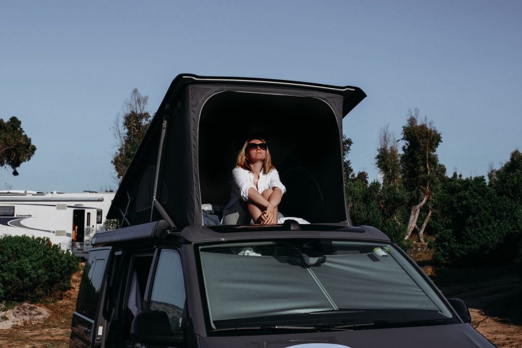 Woman sitting on top of camper van