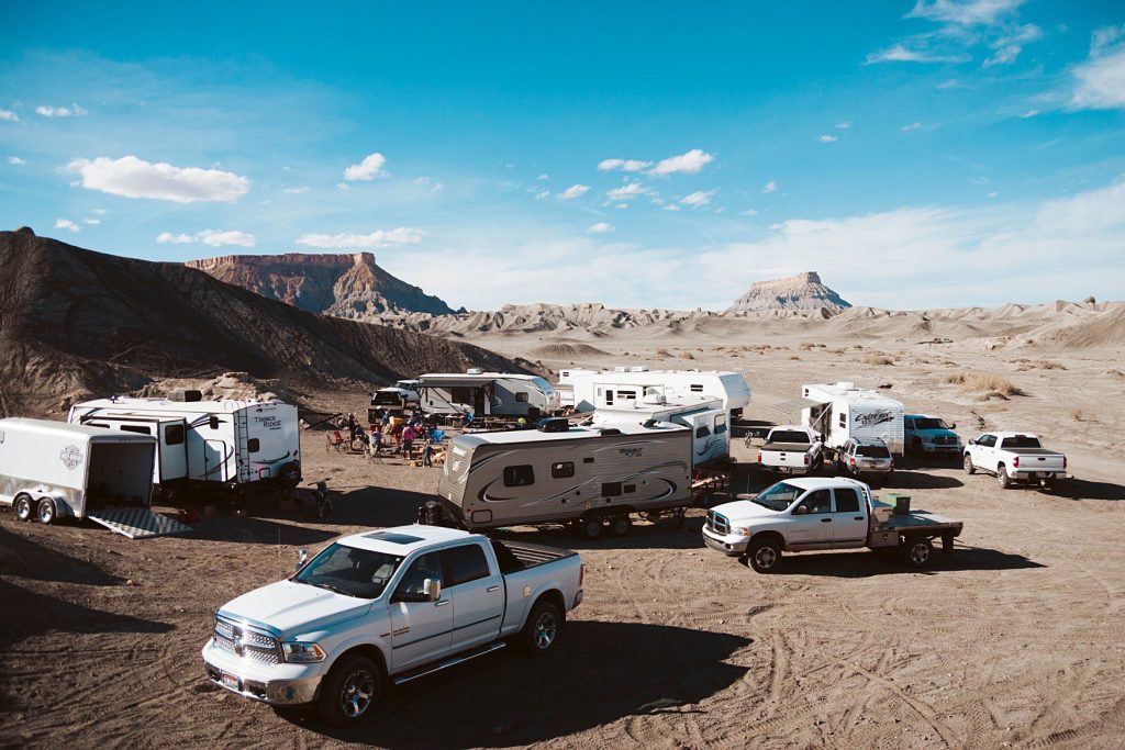 RVs and trucks parked in desert at campsite.