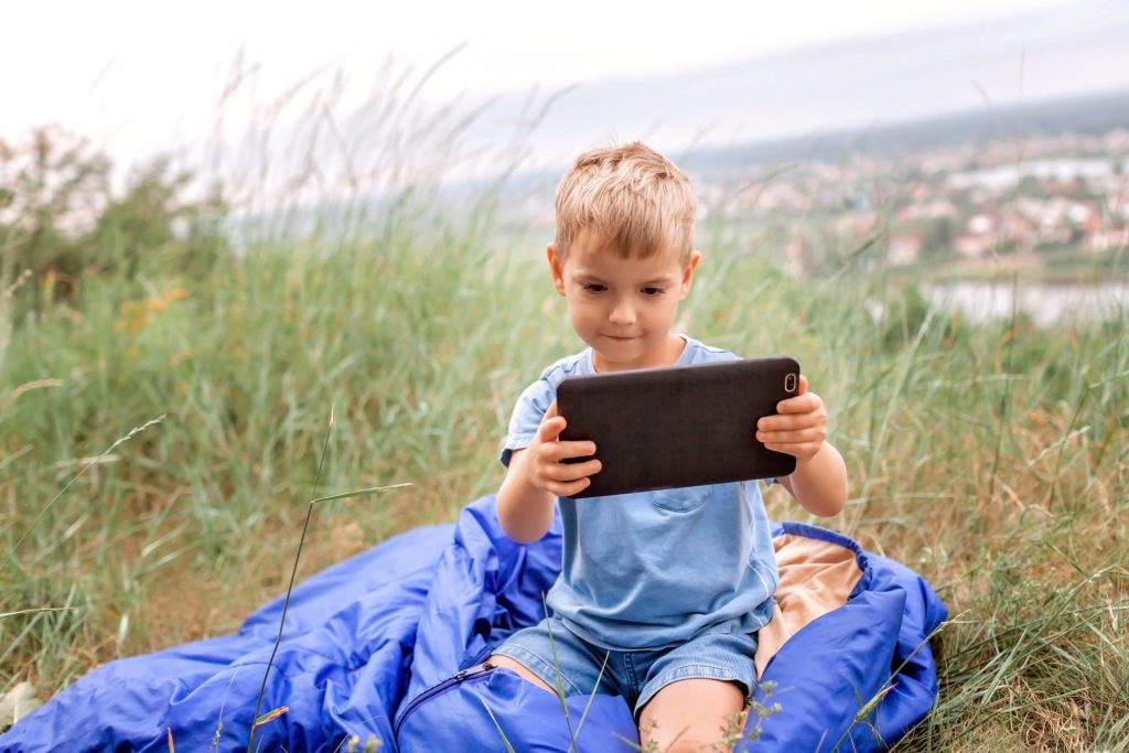 Boy playing on iPad while camping