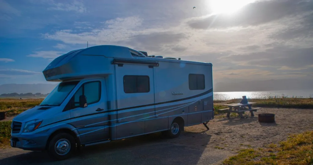 RV parked alongside beach on vacation.