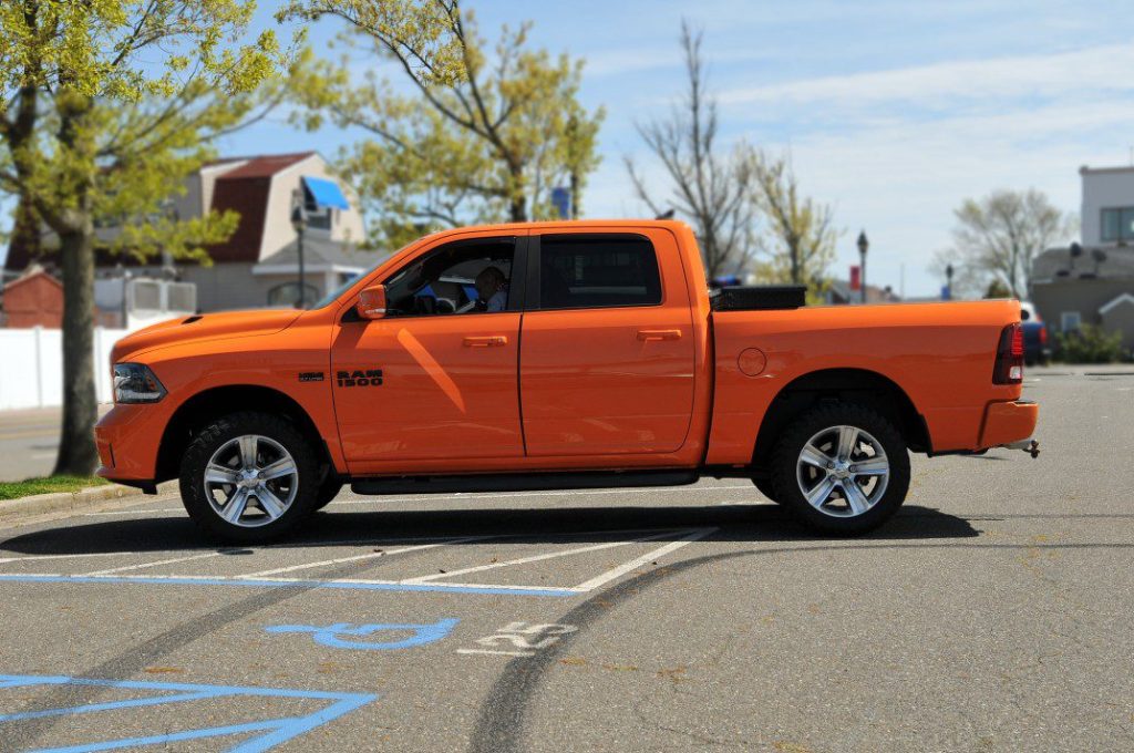 Orange RAM 1500 truck parked in parking lot.