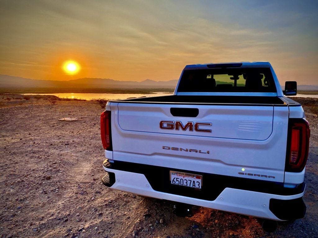 White GMC truck parked in desert at sunset.