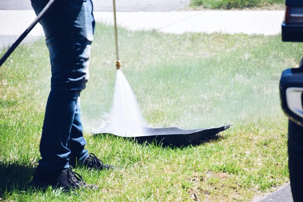 Person running hose on rubber car mat.