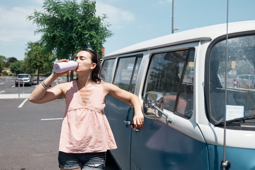 Woman drinking water in front of camper van