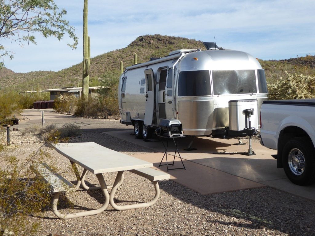Airstream travel trailer hitched to truck in desert.