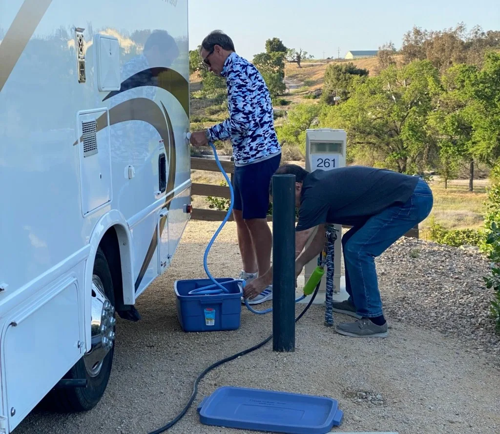 Two people hooking up RV to empty tanks