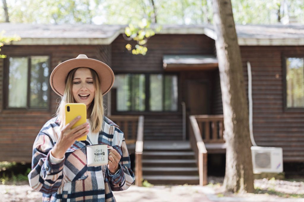 Woman using phone while drinking coffee on a camping trip.