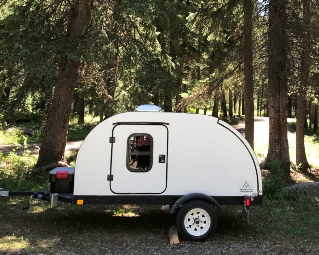 Teardrop camper parked in trees
