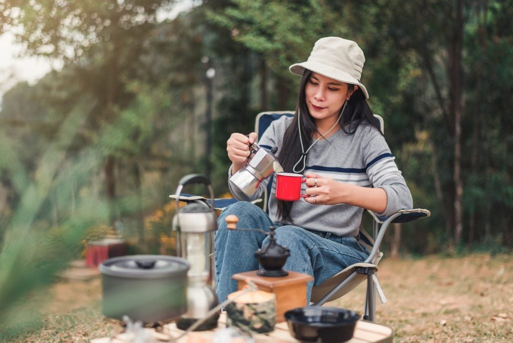 Woman pouring coffee into a mug while solo camping