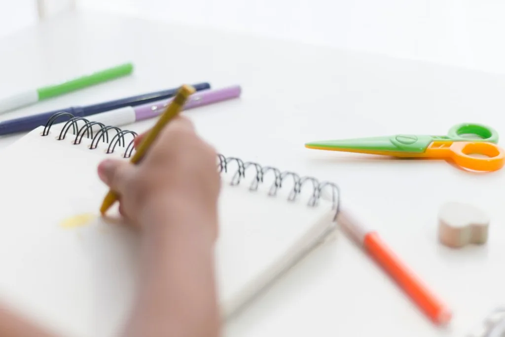 Kid writing with school supplies