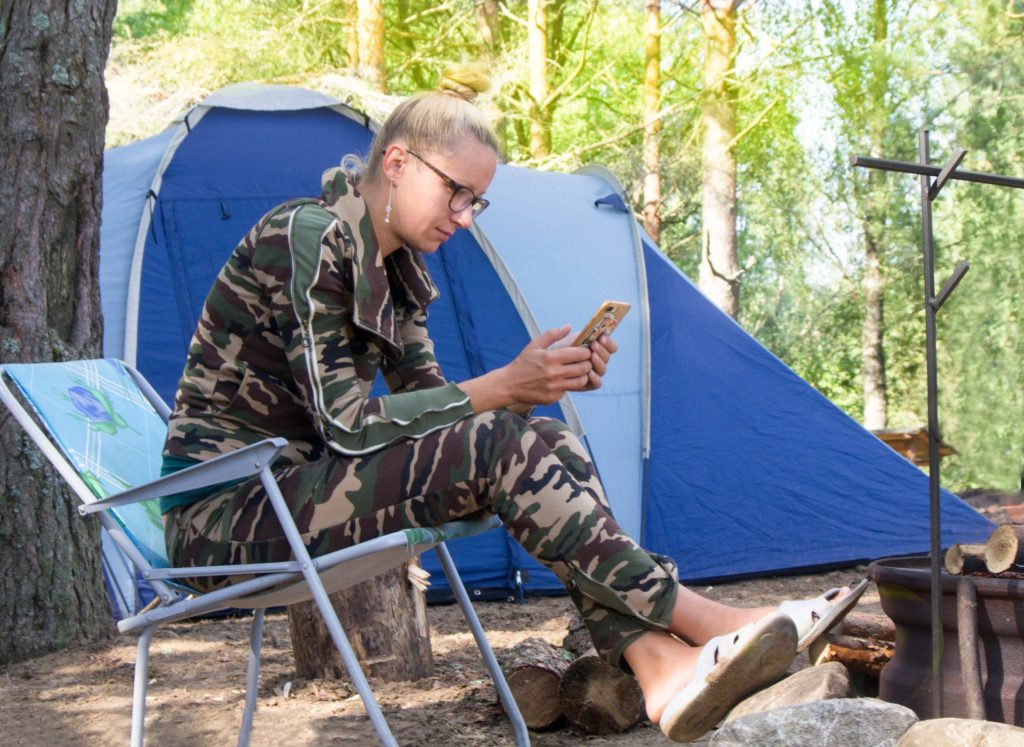 Woman looking at phone while tent camping