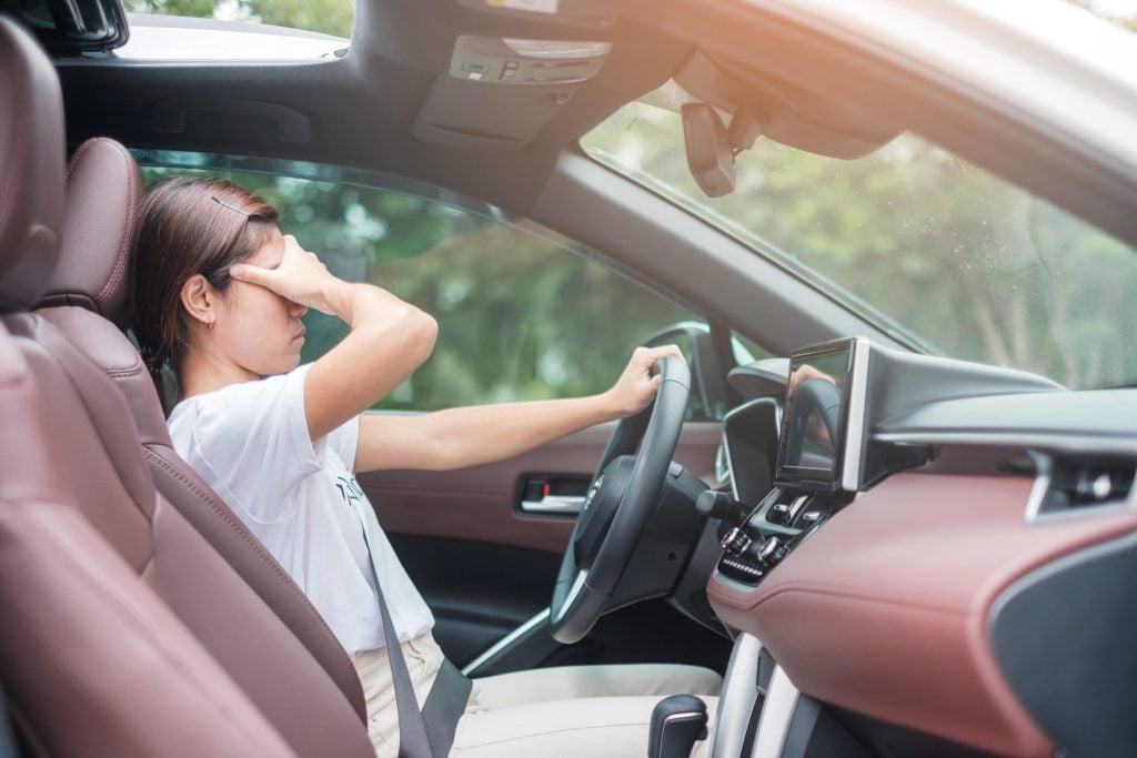 Woman rubbing eyes tired while driving