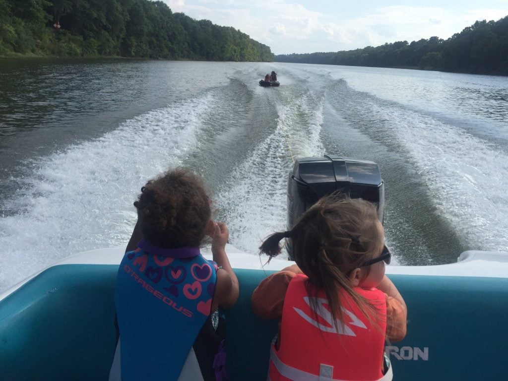 Two kids sitting on a boat driving on the Chattahoochee River