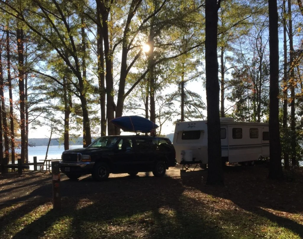 SUV towing camper through treelined forests