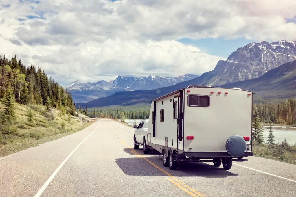 Truck towing trailer on road in mountains