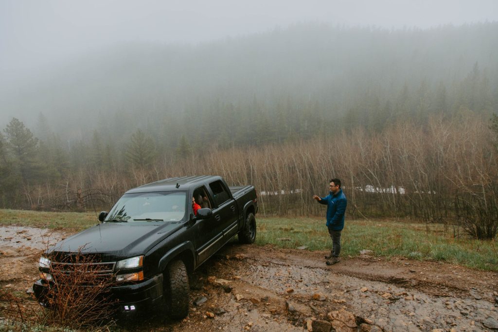 Man helping friend drive truck out of mud