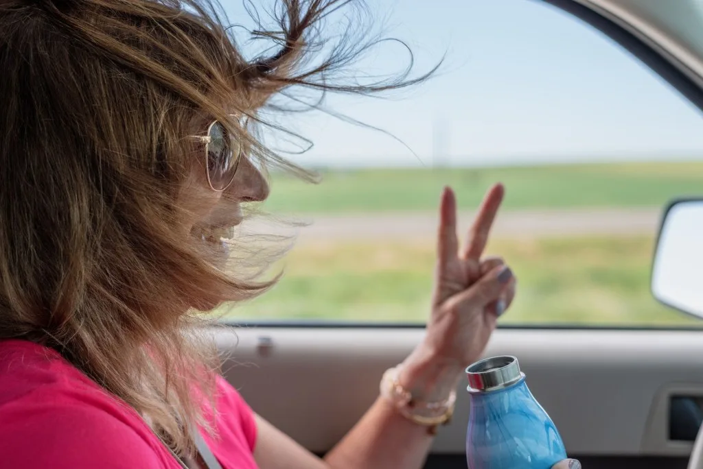 Woman flashing peace sign while driving 