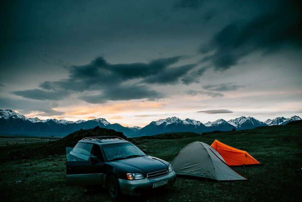 Car and two tents set up for free camping next to mountains