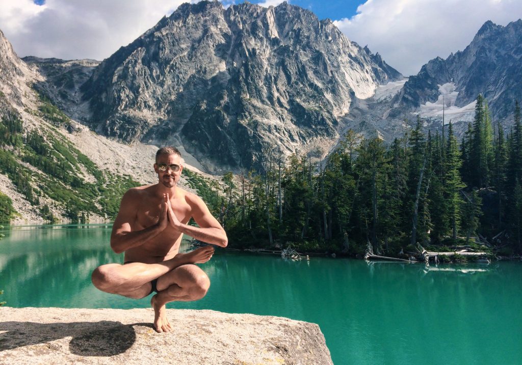 Man doing yoga pose in front of Ross Lake.